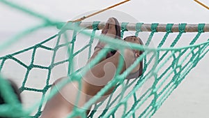 A view of woman`s legs resting on a swinging hammock