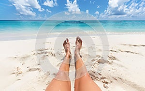 View of woman\'s legs stretched out on the beach facing sea