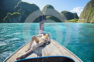 View of woman in swimsuit enjoying on thai traditional longtail Boat over beautiful mountain and ocean, Phi phi Islands, Thailand