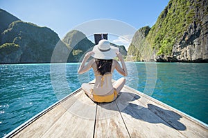 View of woman in swimsuit enjoying on thai traditional longtail Boat over beautiful mountain and ocean, Phi phi Islands, Thailand