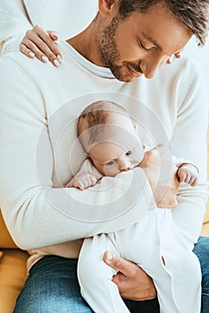 View of woman touching shoulders of husband holding adorable infant