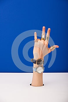 View of woman with wristwatches on hand and golden rings  on blue