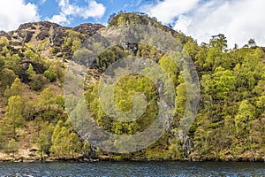 A view of the wooded and rocky southern shore of Loch Katrine in the Scottish Highlands