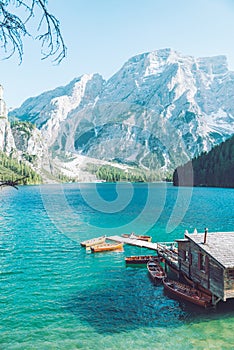 view of wooden house on water with pier and boats lake in dolomites mountains