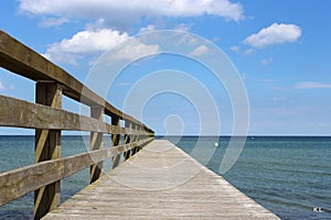 View of a wooden pier into the sea under the cloudy sky