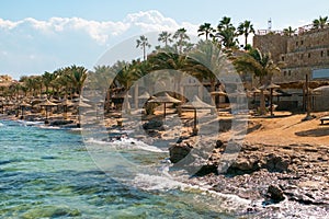 View of a wooden pier on the tropical seashore with blue sky and sea.