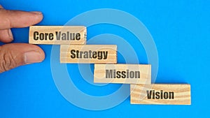 View of Wooden puzzle with text Core Value, Mission, Strategy and Vision on background.