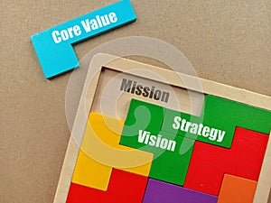 View of Wooden puzzle with text Core Value, Mission, Strategy and Vision on background.