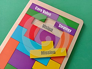 View of Wooden puzzle with text Core Value, Mission, Strategy and Vision on background.