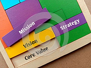 View of Wooden puzzle with text Core Value, Mission, Strategy and Vision on background.