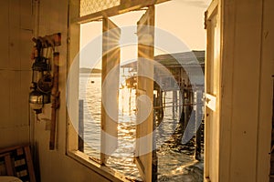view through a wooden window during sunset at a Thai village in the ocean at the fishing town