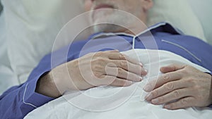 View of wrinkled overworked hands of wise old man peacefully drowsing in bed
