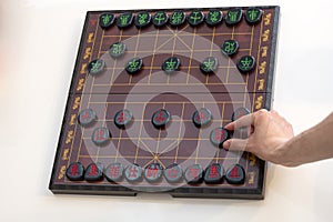 View of a Xiangqi board (Chinese chess) with a hand at the cannon piece