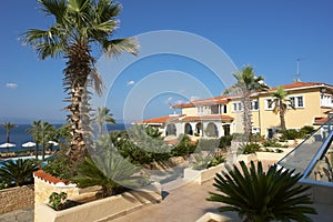 View of the yellow building, the blue sea and green palm trees in the hotel, Greece