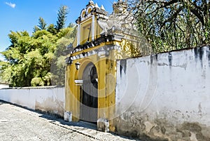 View of Yellow chapel church with crooked cross under blue sky, Antigua, Guatemala