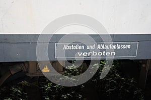 View of yellow electricity logo and warning sign in German below a train wagon