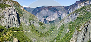 View of Yosemite Valley with Merced river flowing through evergreen forests and Bridalveil Falls visible in the background;