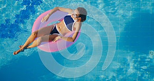 View of young brunette woman swimming on the inflatable pink ring