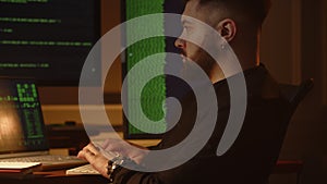 View of a young employee of an IT company working on a laptop in the office. A young programmer sits in front of