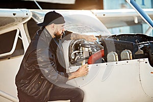 View of young engineer sitting with instruments near light airplane