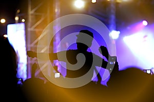 Viewers under the stage. The man with raised hands during summer festival rock concert.