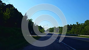 Viewpoint of multiple vehicles on rural street from side of road in summer. Roadside view of transportation traffic approaching