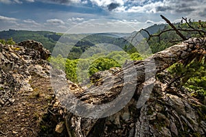 Viewpoint over valley under cloudy sky, old tree stem in foreground photo