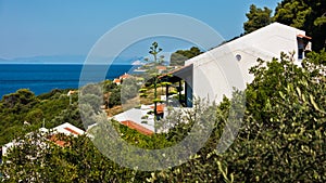Viewpoint from white appartment houses surrounded by greenery at the coast of Skopelos island near Panormos bay