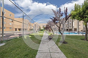 Views of buildings and common areas landscaped with flowers, lawns, trees and summer pools and a tiled path with wooden benche photo