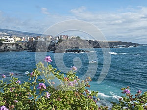 Views of the picturesque Alcala village with traditional architecture houses, small tranquil cove with beach and pier. Pink