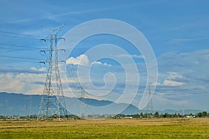 views of rice fields with highvoltage electric towers blue skies and beautiful green rice fields