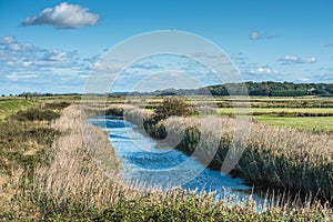 Views of waterway surrounded by reeds, from Norfolk Coast path National Trail near Burnham Overy Staithe