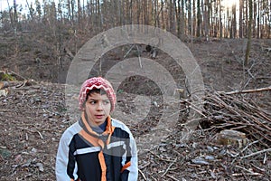 Vigilant expression. The boy faces the camera, his eyes looking away. Autistic child on a forest pass.