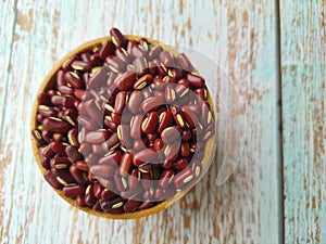 Vigna angularis, in a wooden bowl on a rustic wooden table, top view.