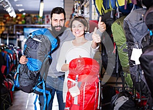 Vigorous couple examining rucksacks in sports equipment store