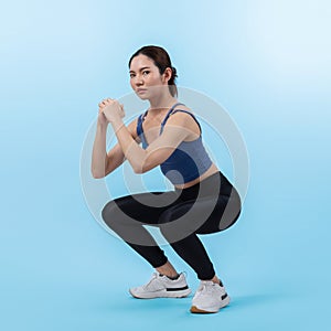 Vigorous energetic woman doing exercise with squat on isolated background.