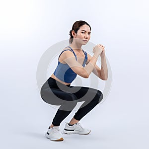 Vigorous energetic woman doing exercise with squat on isolated background.