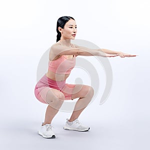 Vigorous energetic woman doing exercise with squat on isolated background.