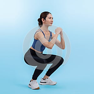 Vigorous energetic woman doing exercise with squat on isolated background.