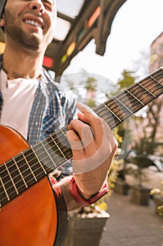 Vigorous male guitarist experimenting with chords on street