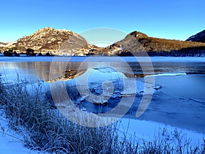 Winterday in Norway at the lake with souroundet with mountains. photo