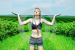 Viking aggressive makeup girl cosplay in a green wheat field. Kneeling, praying to the ancient gods. Paganism, feminism,