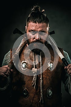Viking with cold weapon in a traditional warrior clothes