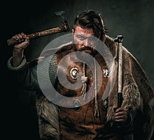 Viking with cold weapon in a traditional warrior clothes