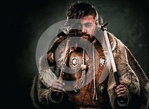 Viking with cold weapon in a traditional warrior clothes