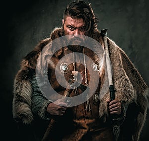 Viking with cold weapon in a traditional warrior clothes