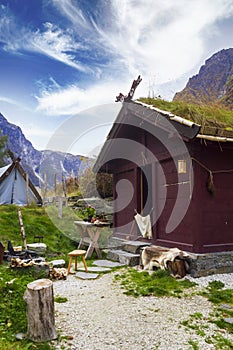 Viking village in Norway with wooden houses, tents with mountains surrounding. Norwegian fjord landscape