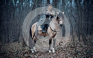 Viking warrior female ridding a horse at twilight autumn forest - Medieval movie scene photo