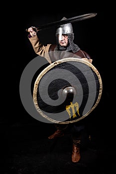 Viking warrior with a shield and a sword in a pose of threat, full-length portrait