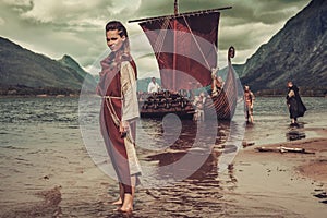 Viking woman standing near Drakkar on seashore